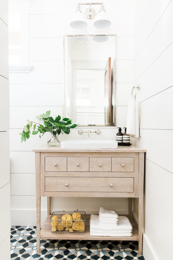 Inspiration for a transitional powder room in Salt Lake City with white walls, cement tiles, multi-coloured floor, furniture-like cabinets, light wood cabinets, a vessel sink, wood benchtops and beige benchtops.