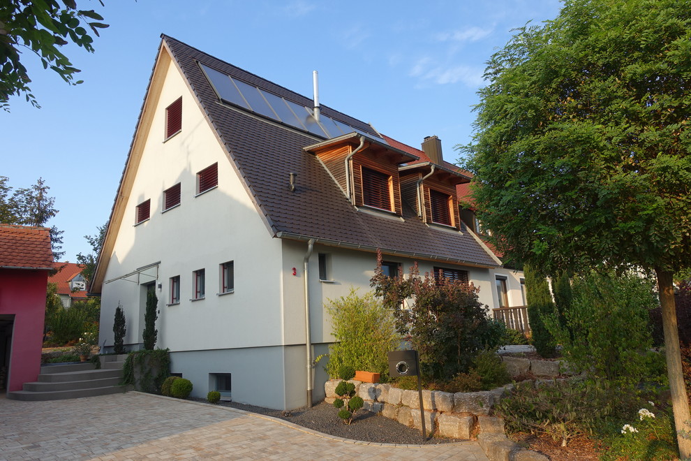 Small contemporary two-storey stucco beige duplex exterior in Nuremberg with a gable roof and a tile roof.
