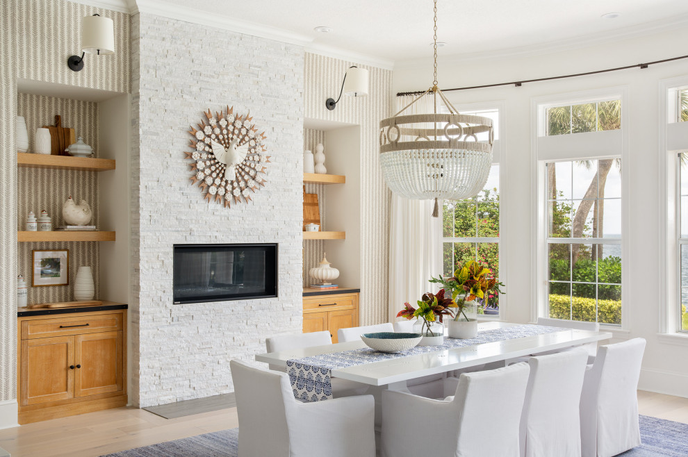 Inspiration for a mid-sized mediterranean kitchen/dining combo in Tampa with white walls, medium hardwood floors, a standard fireplace and a metal fireplace surround.