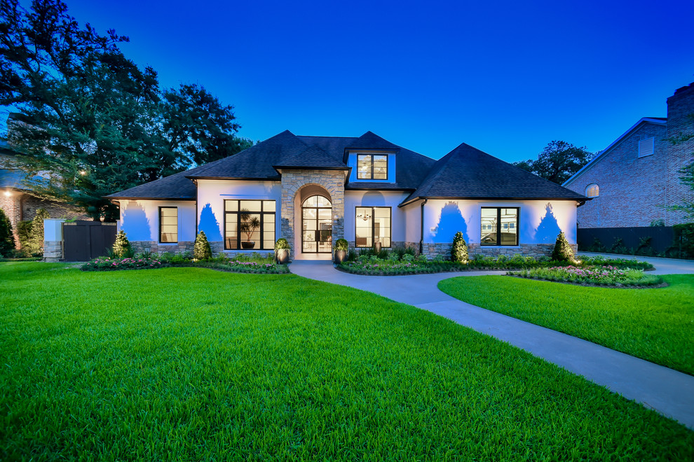 Large contemporary two-storey stucco white house exterior in Houston with a gable roof and a shingle roof.