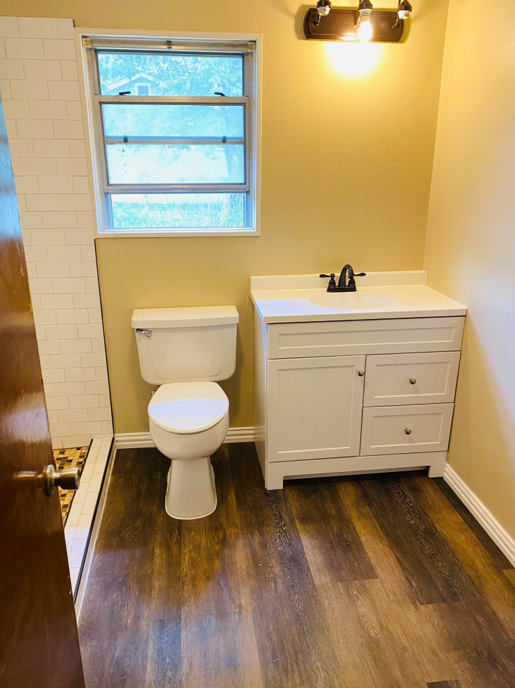 This is an example of a small master bathroom in Dallas with white cabinets, an open shower, white tile, ceramic tile, vinyl floors, solid surface benchtops, brown floor, white benchtops, a niche, a single vanity and a freestanding vanity.