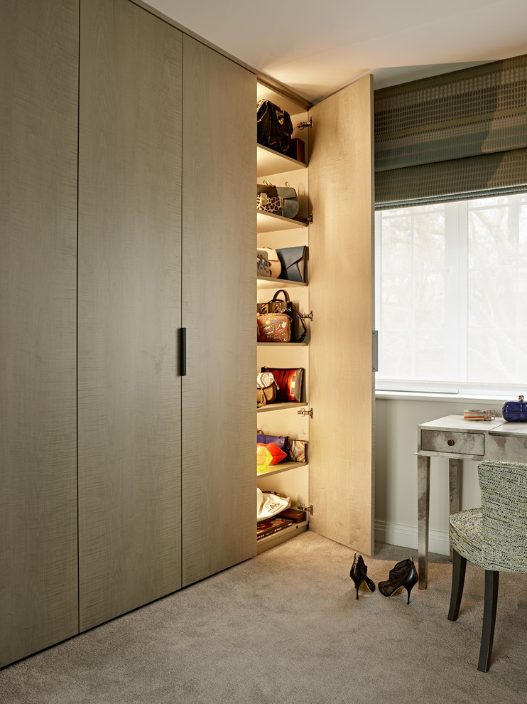 Photo of a mid-sized contemporary gender-neutral dressing room in London with carpet, beige floor, flat-panel cabinets and light wood cabinets.