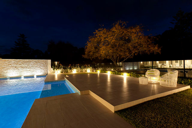 Expansive modern backyard formal garden in Sydney with natural stone pavers.