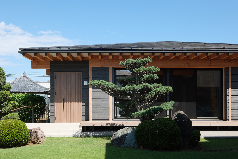 На фото: одноэтажный, черный частный загородный дом среднего размера в классическом стиле с комбинированной облицовкой, вальмовой крышей, металлической крышей, черной крышей и отделкой планкеном