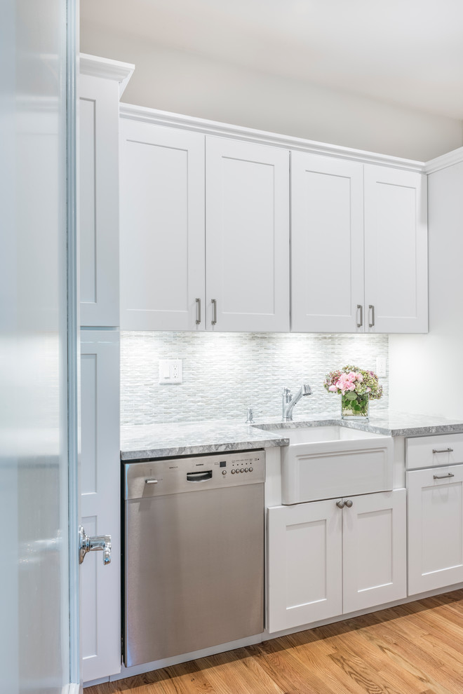 Inspiration for a large traditional eat-in kitchen in Boston with glass-front cabinets, white cabinets, quartzite benchtops, white splashback, stainless steel appliances, medium hardwood floors, with island and brown floor.