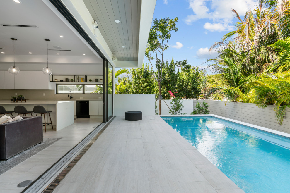 Foto de piscina alargada minimalista pequeña rectangular en patio trasero con suelo de baldosas