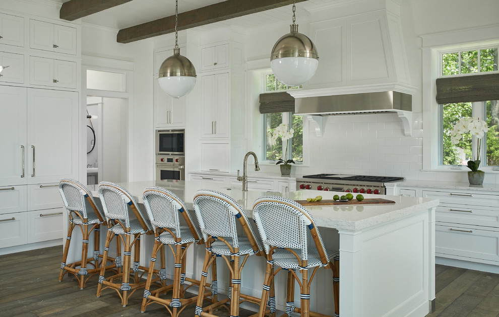 Large beach style l-shaped separate kitchen in Grand Rapids with white cabinets, white splashback, with island, subway tile splashback, a farmhouse sink, beaded inset cabinets, quartz benchtops, panelled appliances, medium hardwood floors and white benchtop.