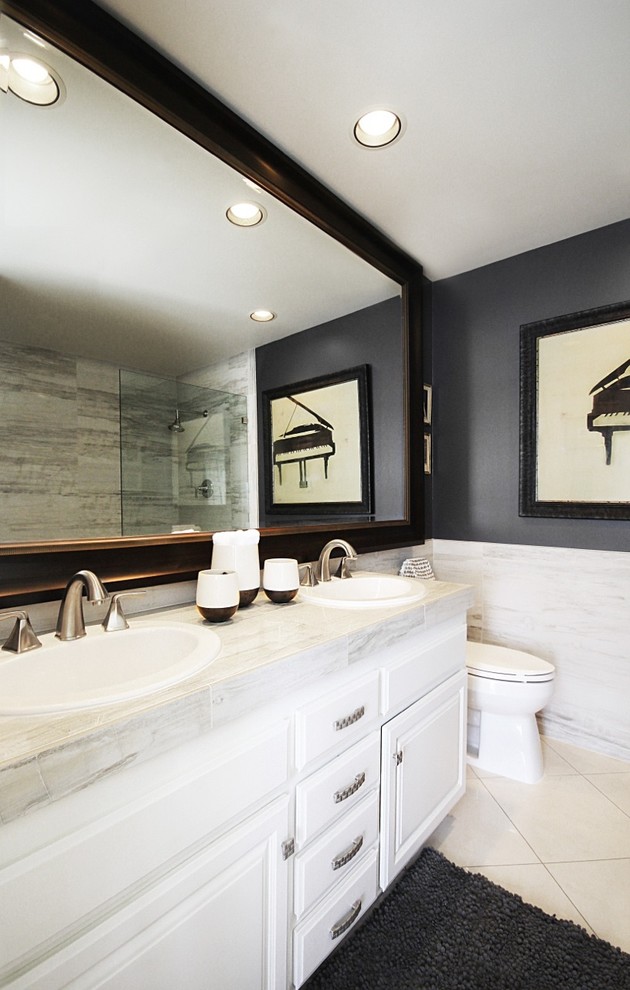 This is an example of a mid-sized modern bathroom with white cabinets, an open shower, a one-piece toilet, black walls, a drop-in sink, tile benchtops, white floor, white benchtops, marble floors, an open shower, a double vanity, raised-panel cabinets, white tile, an enclosed toilet and a built-in vanity.