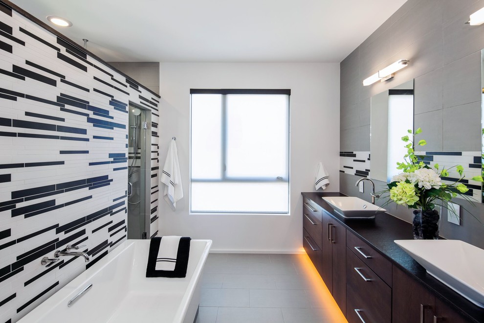 This is an example of a contemporary master bathroom in Austin with a vessel sink, flat-panel cabinets, dark wood cabinets, a freestanding tub, multi-coloured tile, matchstick tile and white walls.
