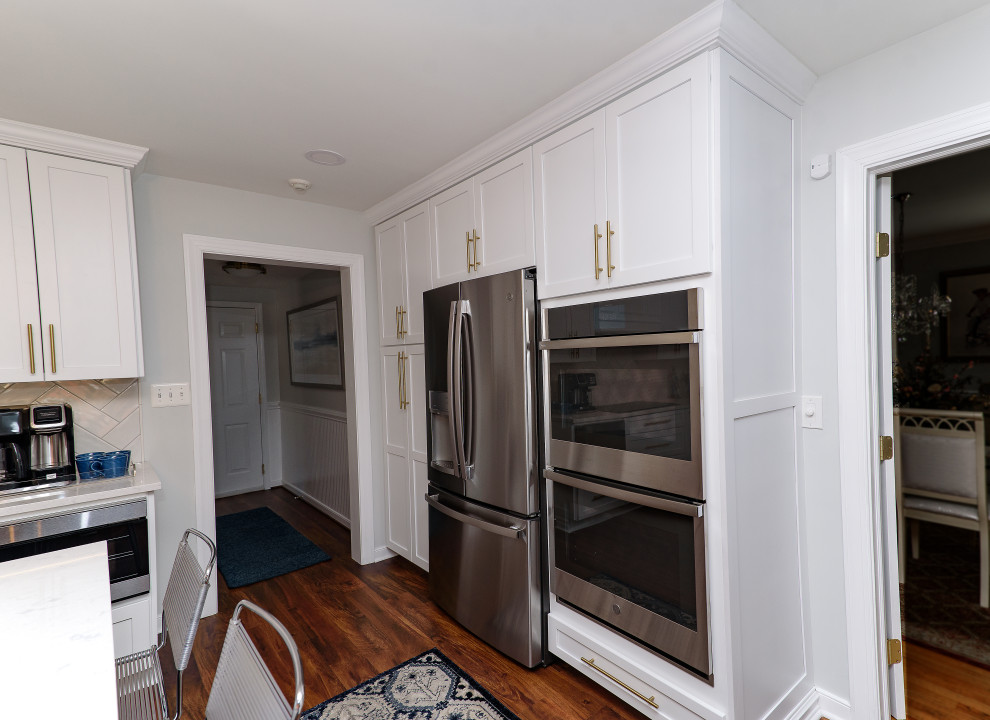 Inspiration for a mid-sized transitional galley brown floor and medium tone wood floor eat-in kitchen remodel in Baltimore with shaker cabinets, white cabinets, quartz countertops, white backsplash, subway tile backsplash, stainless steel appliances, an island, white countertops and an undermount sink