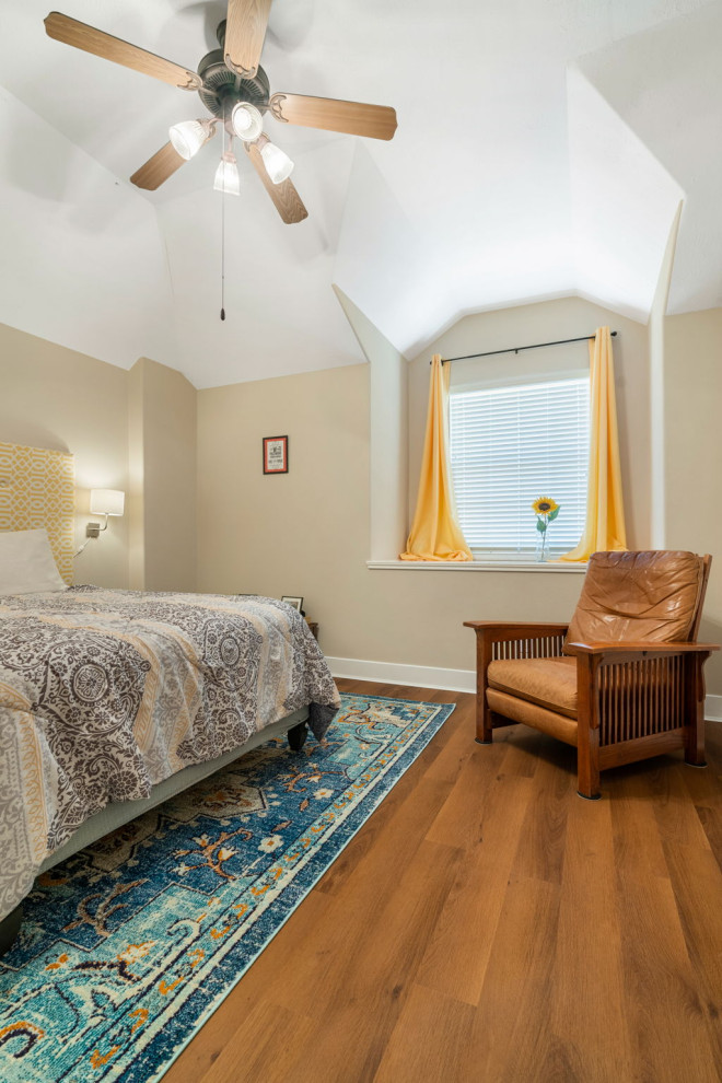 Modelo de habitación de invitados abovedada de estilo americano de tamaño medio con paredes beige, suelo vinílico y suelo marrón