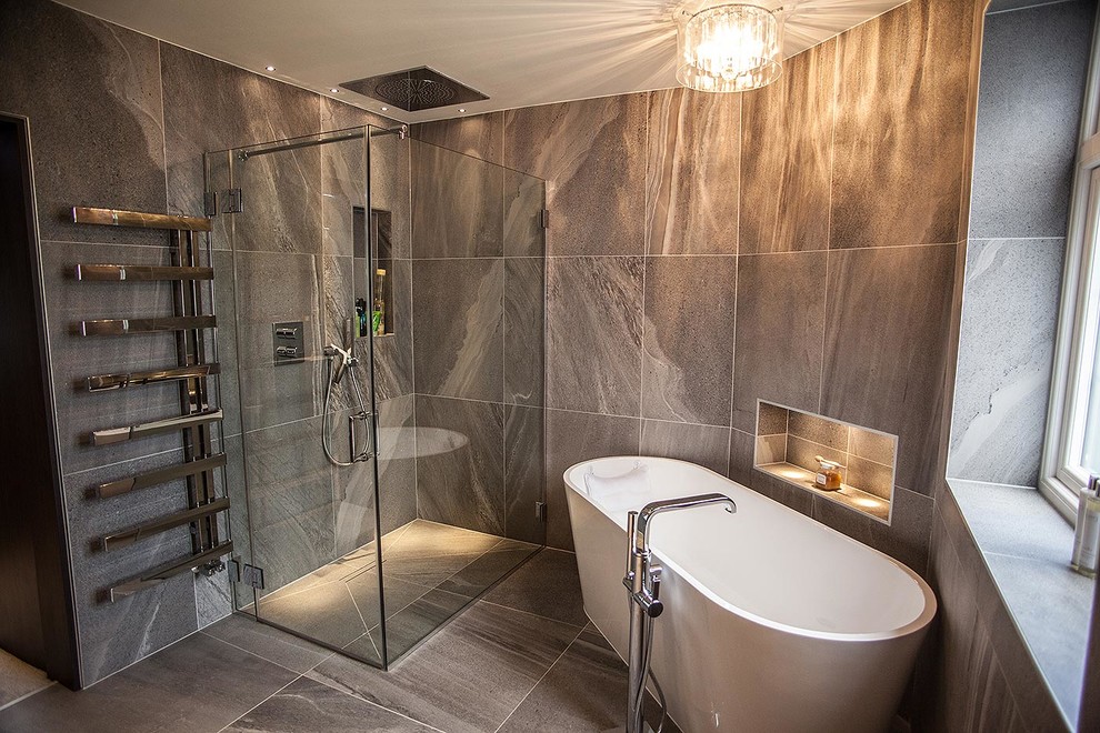 Photo of a large contemporary bathroom in London with a freestanding tub, an open shower, a wall-mount toilet, gray tile, porcelain tile, grey walls, porcelain floors and a drop-in sink.