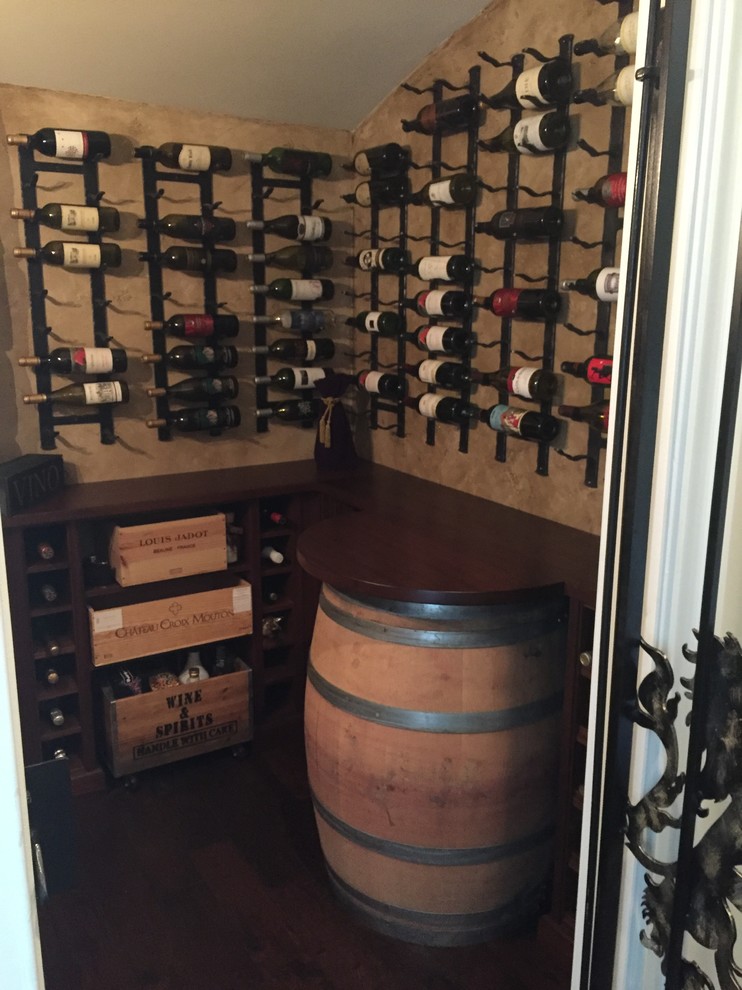 Inspiration for a mid-sized country wine cellar in Other with dark hardwood floors, storage racks and brown floor.