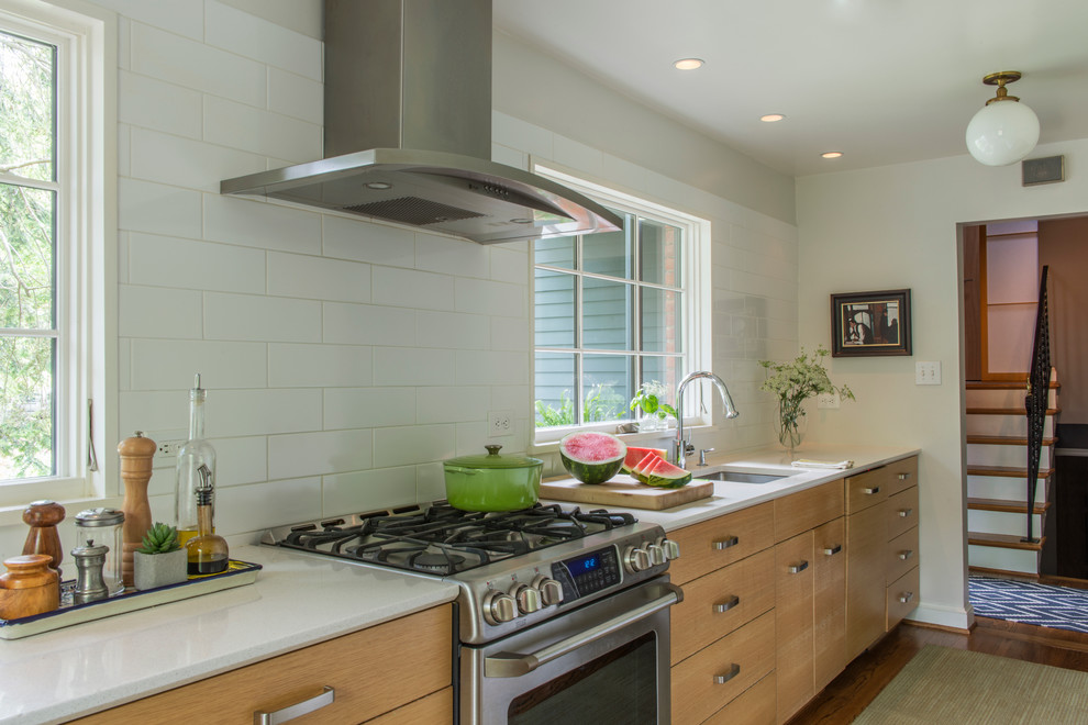 Inspiration for a mid-sized transitional galley medium tone wood floor enclosed kitchen remodel in DC Metro with an undermount sink, flat-panel cabinets, light wood cabinets, quartz countertops, white backsplash, ceramic backsplash, stainless steel appliances and no island