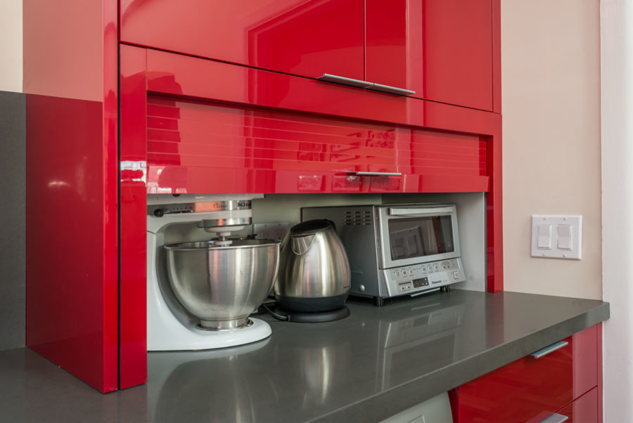 Inspiration for a mid-sized contemporary u-shaped eat-in kitchen in San Francisco with an undermount sink, flat-panel cabinets, red cabinets, quartz benchtops, grey splashback, stainless steel appliances, travertine splashback, linoleum floors, a peninsula and grey floor.