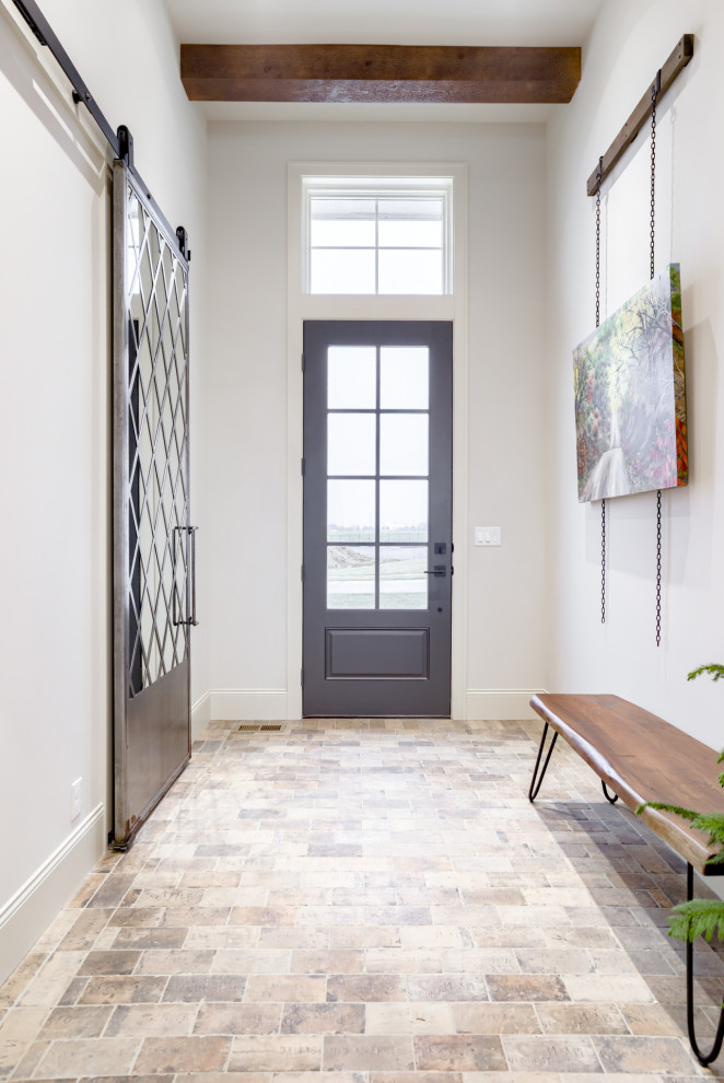 На фото: входная дверь в классическом стиле с кирпичным полом, одностворчатой входной дверью, черной входной дверью и балками на потолке с
