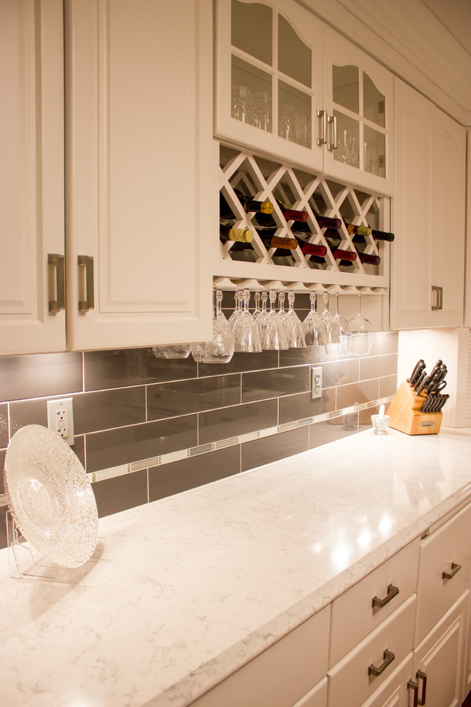 Example of a transitional kitchen design in Cedar Rapids with raised-panel cabinets, white cabinets, quartz countertops, black backsplash and subway tile backsplash