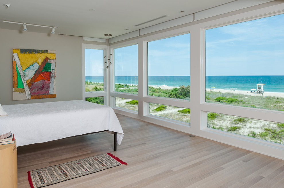 Photo of a large beach style master bedroom in Wilmington with white walls and linoleum floors.