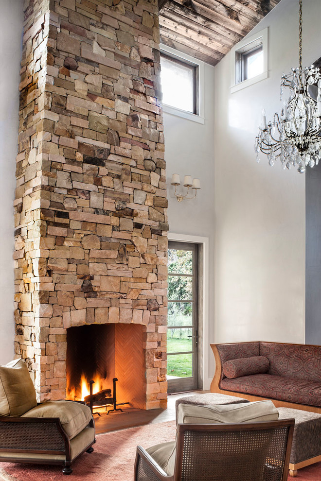 Inspiration for a country open concept living room in Los Angeles with grey walls, no tv, light hardwood floors, a standard fireplace, a stone fireplace surround and brown floor.