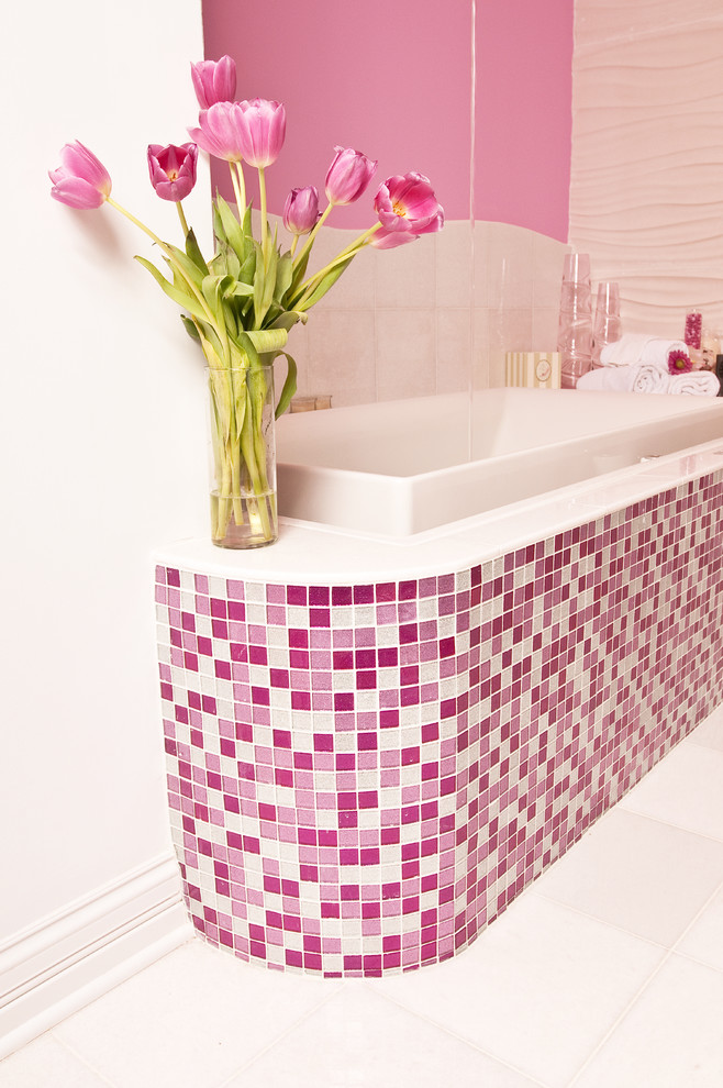 This is an example of a large contemporary kids bathroom in New York with open cabinets, a drop-in tub, a one-piece toilet, pink tile, mosaic tile, pink walls, ceramic floors, a wall-mount sink, glass benchtops, white floor and a corner shower.