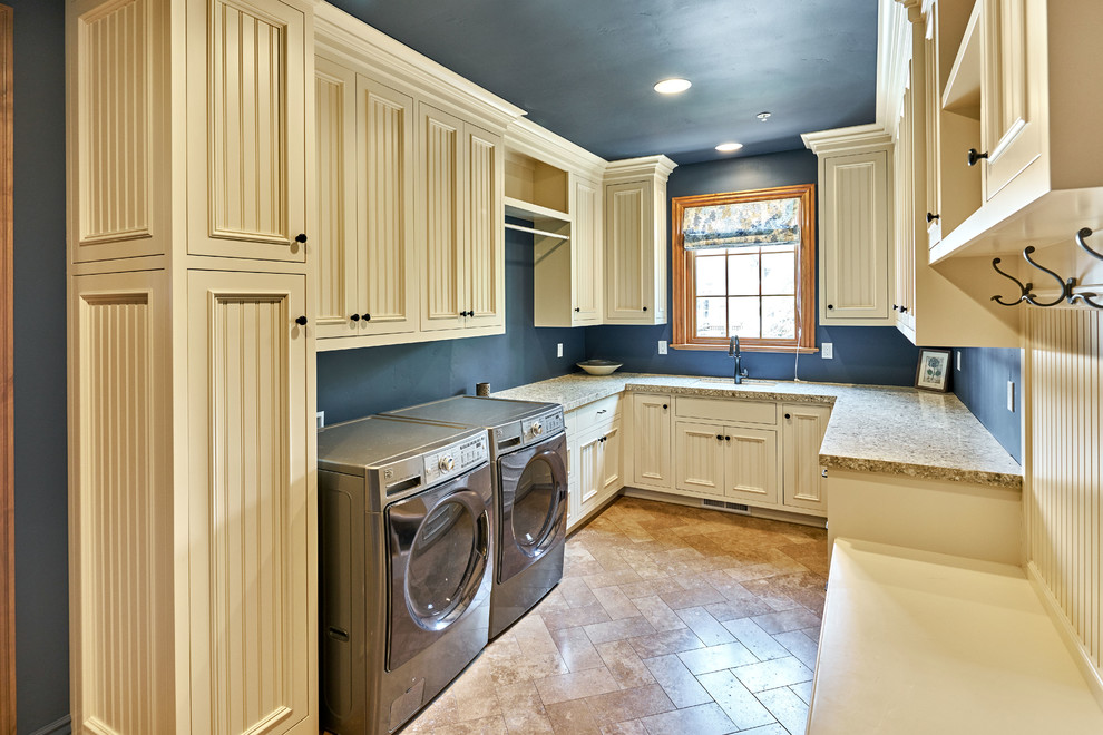 This is an example of an expansive traditional u-shaped utility room in San Francisco with an undermount sink, recessed-panel cabinets, white cabinets, granite benchtops, blue walls, travertine floors and a side-by-side washer and dryer.