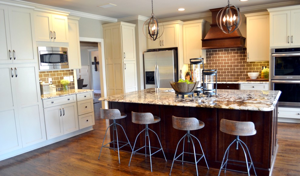Eat-in kitchen - mid-sized transitional l-shaped medium tone wood floor eat-in kitchen idea with an undermount sink, shaker cabinets, distressed cabinets, granite countertops, gray backsplash, subway tile backsplash, stainless steel appliances and an island