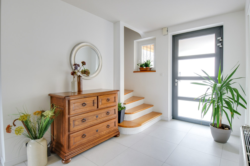 This is an example of a mid-sized contemporary foyer in Strasbourg with white walls, ceramic floors, a single front door, a gray front door and beige floor.