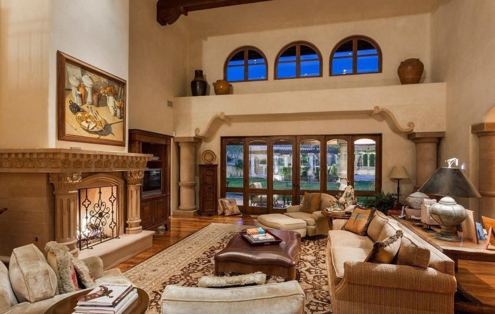Expansive traditional open concept family room in Phoenix with beige walls, light hardwood floors, a standard fireplace, a stone fireplace surround, a wall-mounted tv and brown floor.