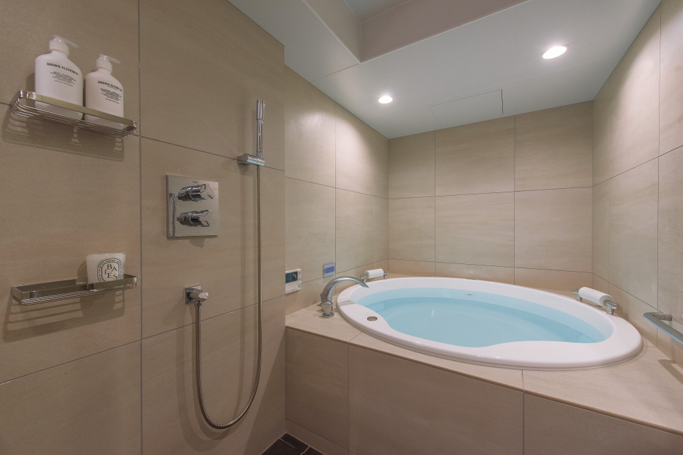 Bathroom with a hot tub, beige tile, porcelain tile, beige walls, cork floors and brown floor.