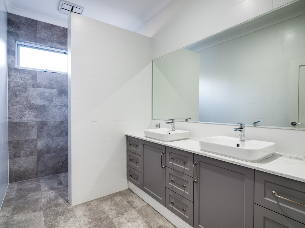 Стильный дизайн: большая серо-белая ванная комната в стиле модернизм с открытыми фасадами, белыми фасадами, отдельно стоящей ванной, открытым душем, унитазом-моноблоком, разноцветной плиткой, белыми стенами, полом из цементной плитки, душевой кабиной, разноцветным полом, открытым душем, разноцветной столешницей, акцентной стеной, тумбой под две раковины, встроенной тумбой, многоуровневым потолком, кирпичными стенами, керамической плиткой, настольной раковиной и столешницей из искусственного кварца - последний тренд