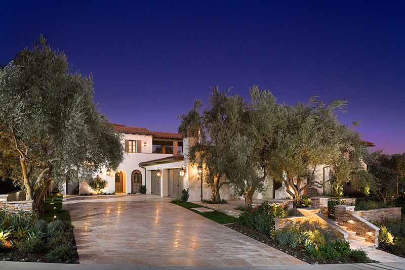 This is an example of a large mediterranean front yard driveway in Orange County with a retaining wall.