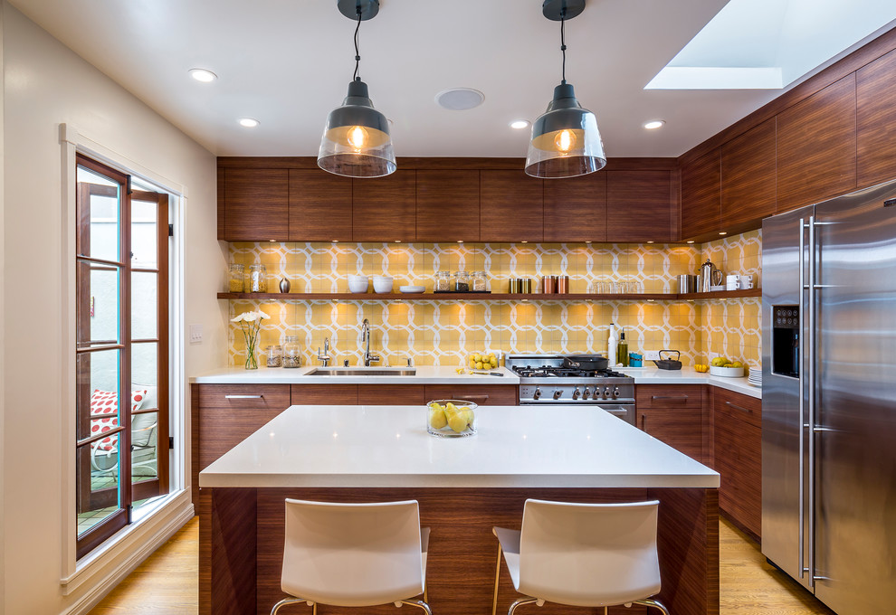 Example of a trendy l-shaped light wood floor and yellow floor kitchen design in San Francisco with an undermount sink, flat-panel cabinets, dark wood cabinets, yellow backsplash, stainless steel appliances and an island