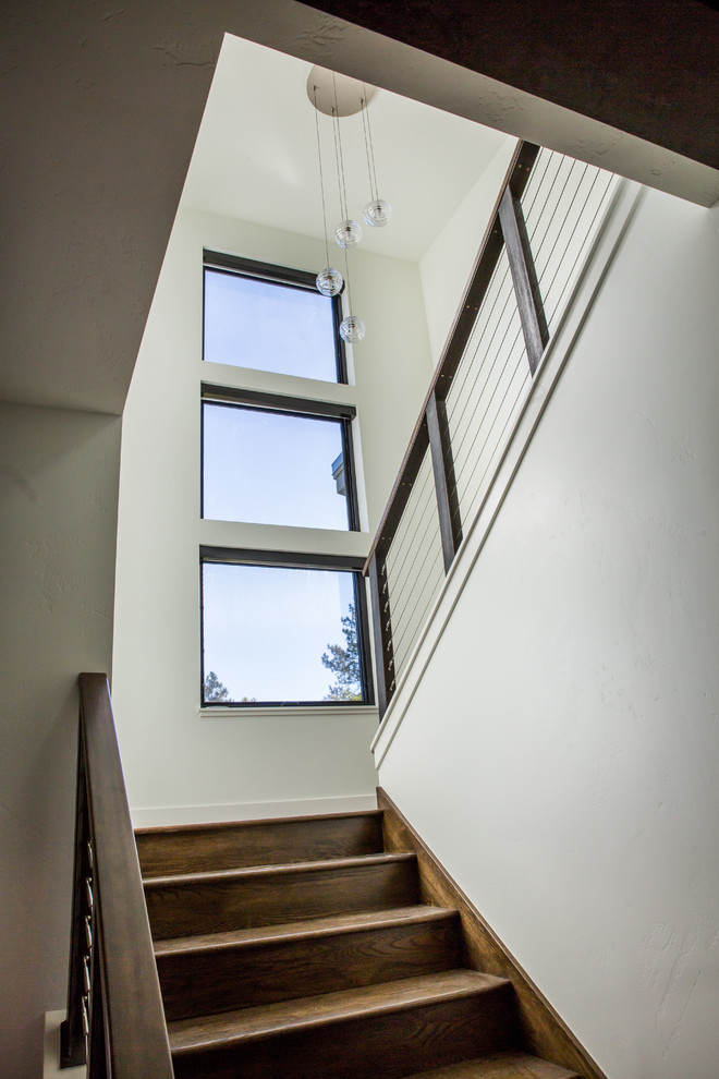 Example of a large transitional wooden u-shaped cable railing staircase design with wooden risers