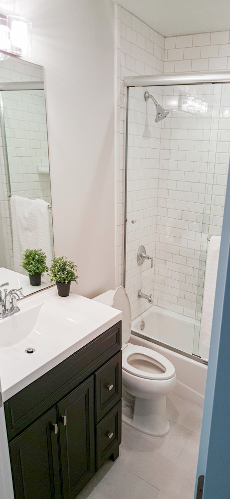 This is an example of a small traditional family bathroom in Los Angeles with recessed-panel cabinets, green cabinets, an alcove bath, an alcove shower, a two-piece toilet, white tiles, metro tiles, grey walls, ceramic flooring, an integrated sink, solid surface worktops, grey floors, a sliding door, white worktops, a single sink and a floating vanity unit.