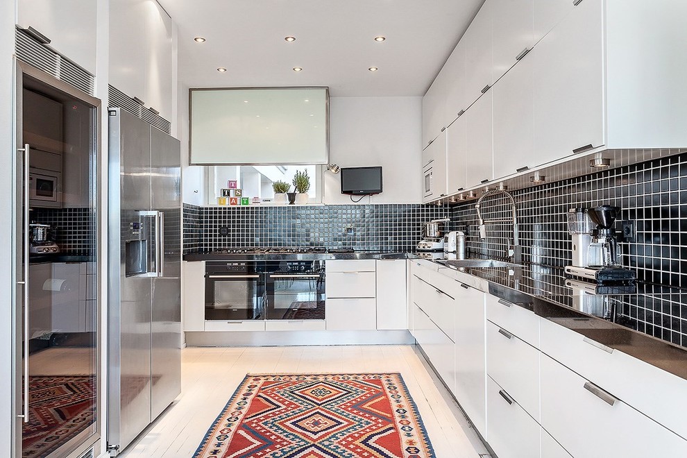 Large contemporary u-shaped kitchen in Stockholm with an undermount sink, flat-panel cabinets, white cabinets, black splashback, ceramic splashback, no island, stainless steel appliances and painted wood floors.