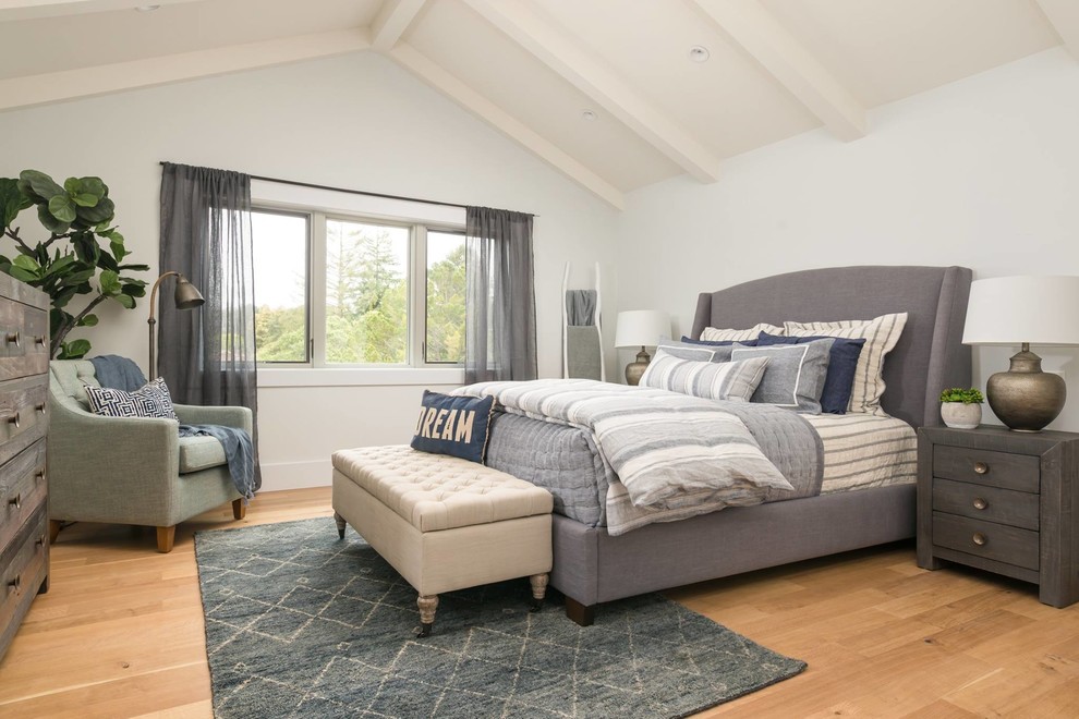 Transitional medium tone wood floor bedroom photo with white walls