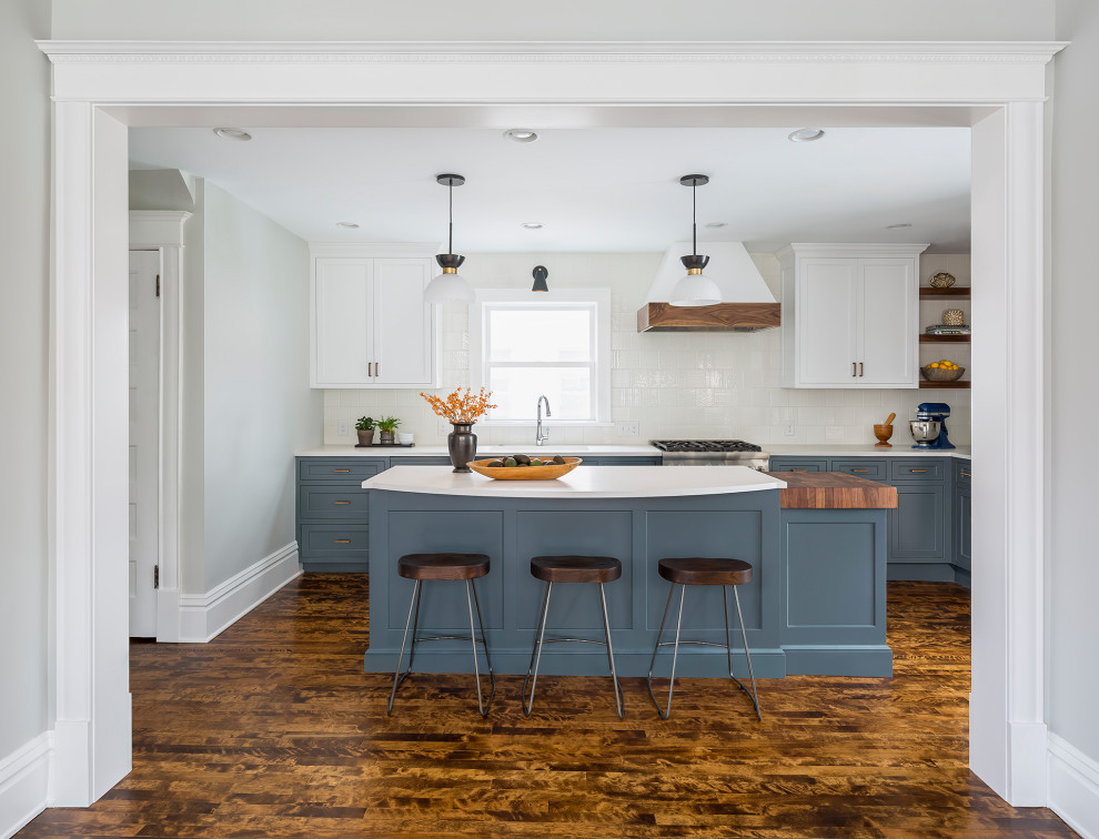 Inspiration for a large transitional l-shaped dark wood floor and brown floor eat-in kitchen remodel in Minneapolis with an undermount sink, flat-panel cabinets, blue cabinets, quartz countertops, white backsplash, ceramic backsplash, paneled appliances, an island and white countertops