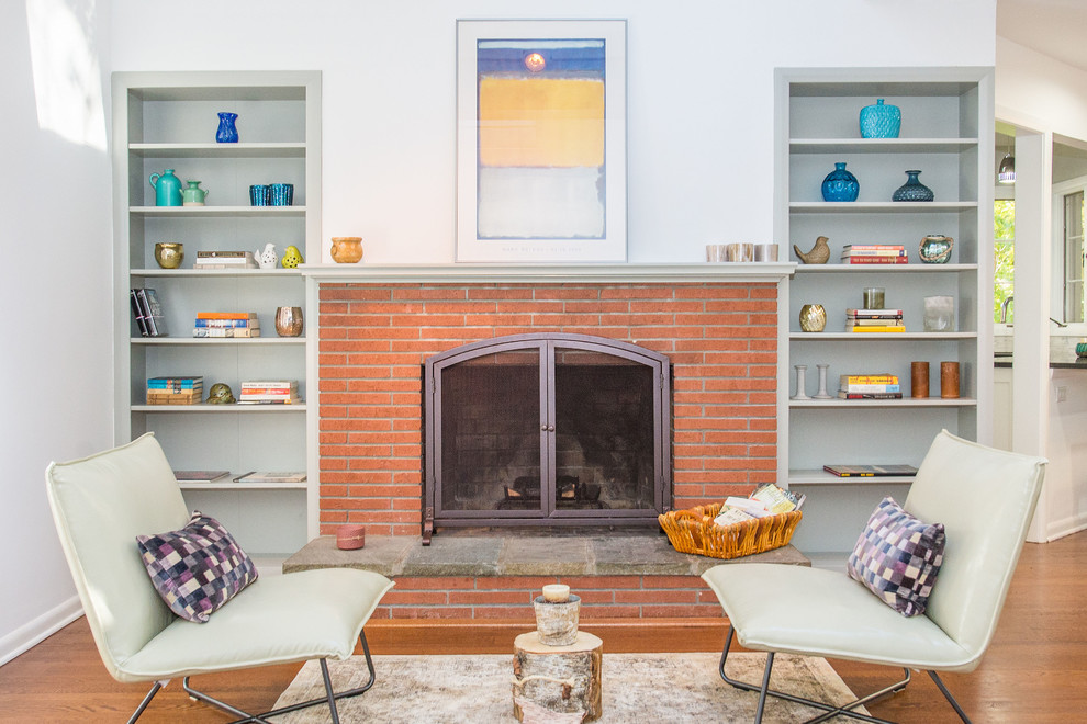 This is an example of a transitional formal living room in New York with blue walls, medium hardwood floors, a standard fireplace, a brick fireplace surround and no tv.