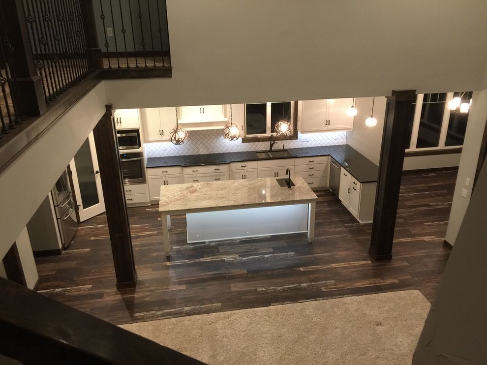 Kitchen - mid-sized transitional laminate floor kitchen idea in Minneapolis with white cabinets, subway tile backsplash and stainless steel appliances