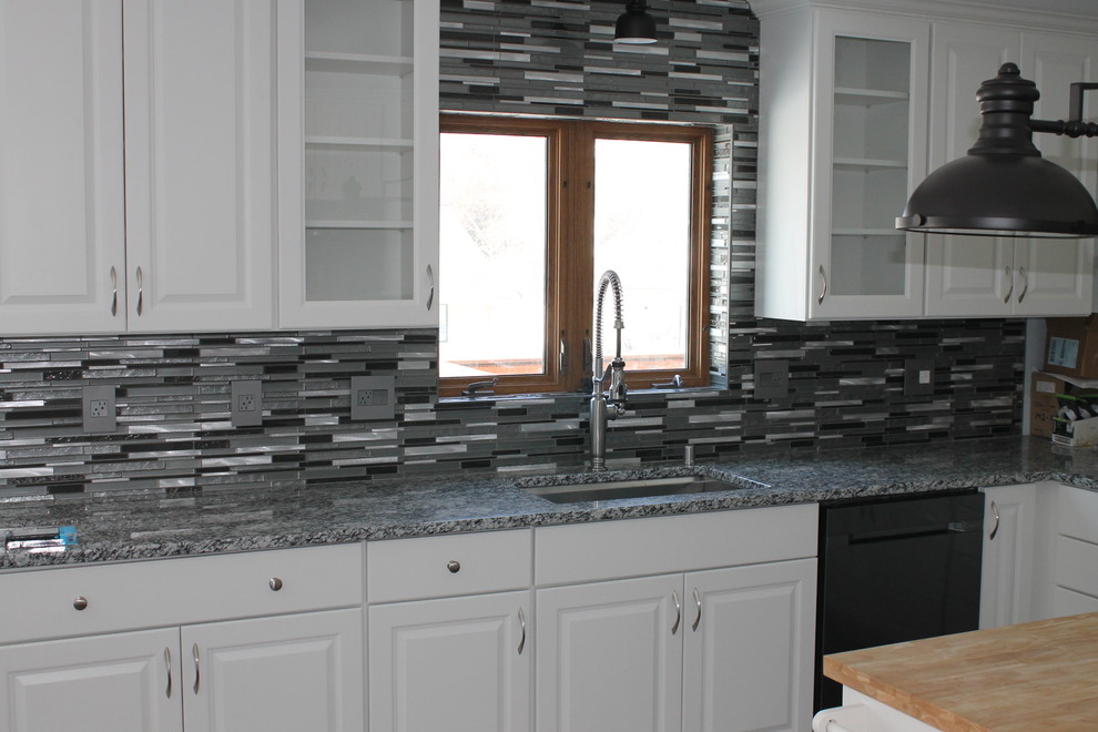 Inspiration for a mid-sized transitional u-shaped dark wood floor and brown floor kitchen remodel with an undermount sink, raised-panel cabinets, white cabinets, granite countertops, multicolored backsplash, matchstick tile backsplash, stainless steel appliances and an island