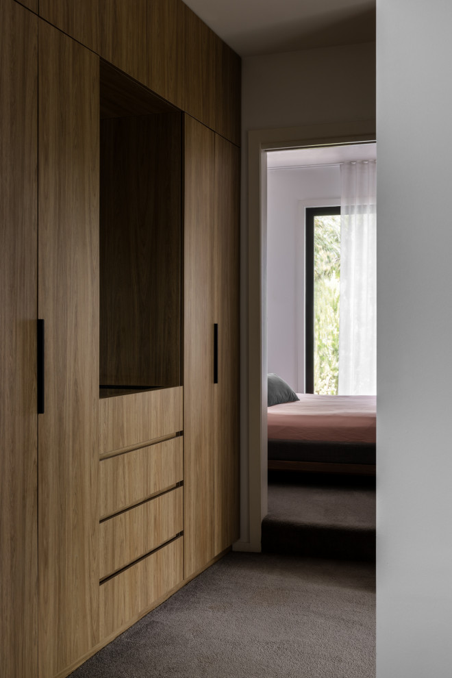 Photo of a medium sized contemporary gender neutral built-in wardrobe in Melbourne with carpet.