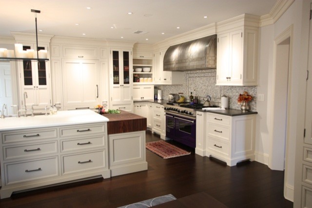 Design ideas for a large transitional l-shaped eat-in kitchen in New York with raised-panel cabinets, white cabinets, grey splashback, white appliances, dark hardwood floors and with island.