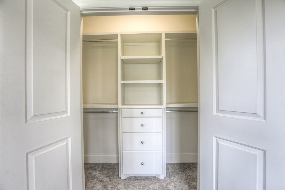 Photo of a small traditional gender-neutral built-in wardrobe in Houston with flat-panel cabinets, white cabinets, carpet and beige floor.