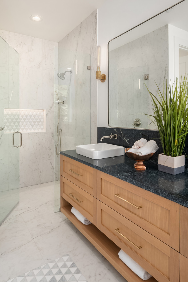 This is an example of a medium sized contemporary ensuite bathroom in Seattle with shaker cabinets, light wood cabinets, a freestanding bath, a built-in shower, a one-piece toilet, white tiles, porcelain tiles, white walls, porcelain flooring, a vessel sink, soapstone worktops, white floors, a hinged door, black worktops, a wall niche, double sinks and a floating vanity unit.