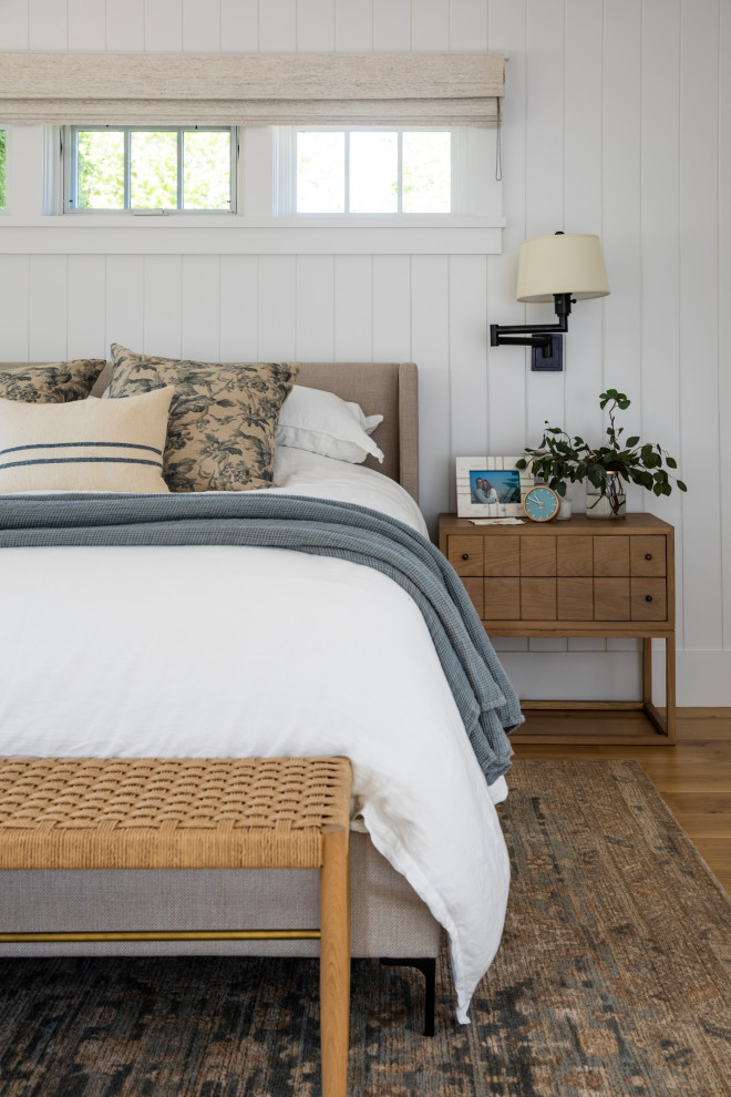 Modelo de dormitorio principal campestre grande con paredes blancas, suelo de madera en tonos medios, suelo marrón y machihembrado