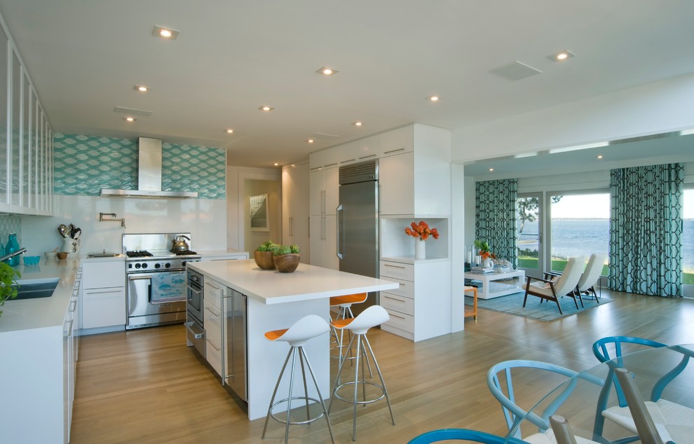 Inspiration for a beach style open plan kitchen in New York with flat-panel cabinets, white cabinets, white splashback and stainless steel appliances.