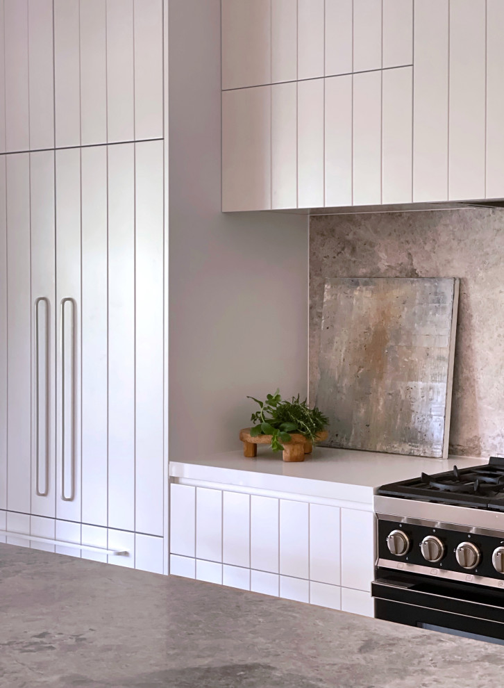 Cette photo montre une grande cuisine tendance avec des portes de placard blanches et un plan de travail en calcaire.