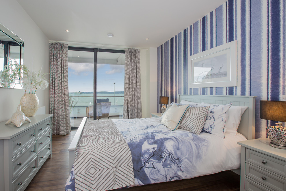 This is an example of a mid-sized beach style guest bedroom in Devon with purple walls, dark hardwood floors, no fireplace, brown floor and wallpaper.