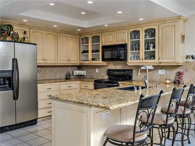 Inspiration for a large transitional u-shaped ceramic tile open concept kitchen remodel in Denver with an undermount sink, raised-panel cabinets, beige cabinets, granite countertops, beige backsplash, terra-cotta backsplash and black appliances