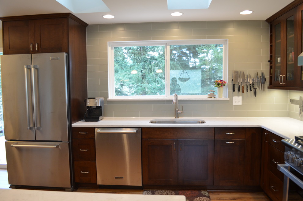 Open concept kitchen - mid-sized transitional l-shaped medium tone wood floor and brown floor open concept kitchen idea in Seattle with an undermount sink, shaker cabinets, dark wood cabinets, quartz countertops, stainless steel appliances, an island, gray backsplash and subway tile backsplash